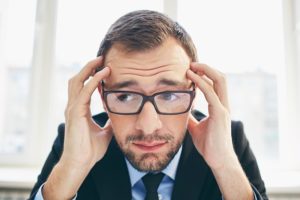 Frustrated businessman in eyeglasses touching his head because he doesn't have any followers on social media
