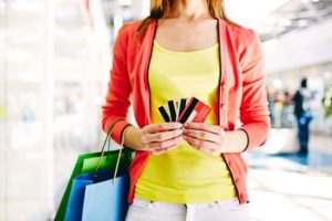 Female customer with plastic cards and shopping bags looking for local business