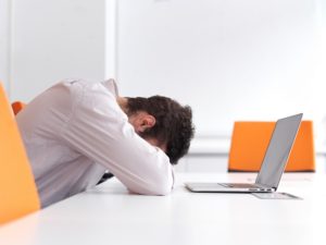 man laying head on desk confused by online marketing