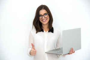 Smiling businesswoman standing with laptop and showing thumb up after reading positive review about company