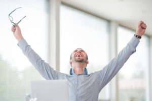 Victorious corporate man celebrating with his arms lifted in the air because he improved website SEO